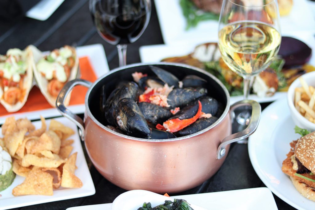 Copper pot of P.E.I. mussels with lobster meat, served alongside red and white wine and small plates