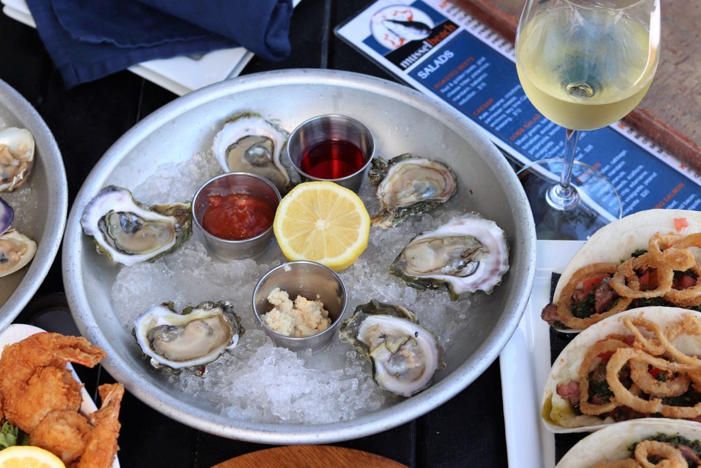 Half-dozen oysters on the half shell on ice with cocktail sauce, mignonette, horseradish, and a lemon wedge