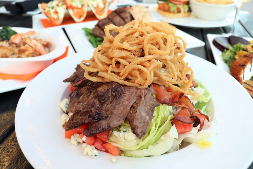 Iceberg Wedge Salad with Skirt Steak - Iceberg, bacon, blue cheese crumbles, cherry tomatoes, frizzled onions, blue cheese dressing.